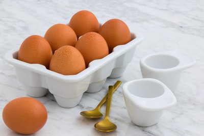 托盘的棕色鸡蛋旁边两个勺子
